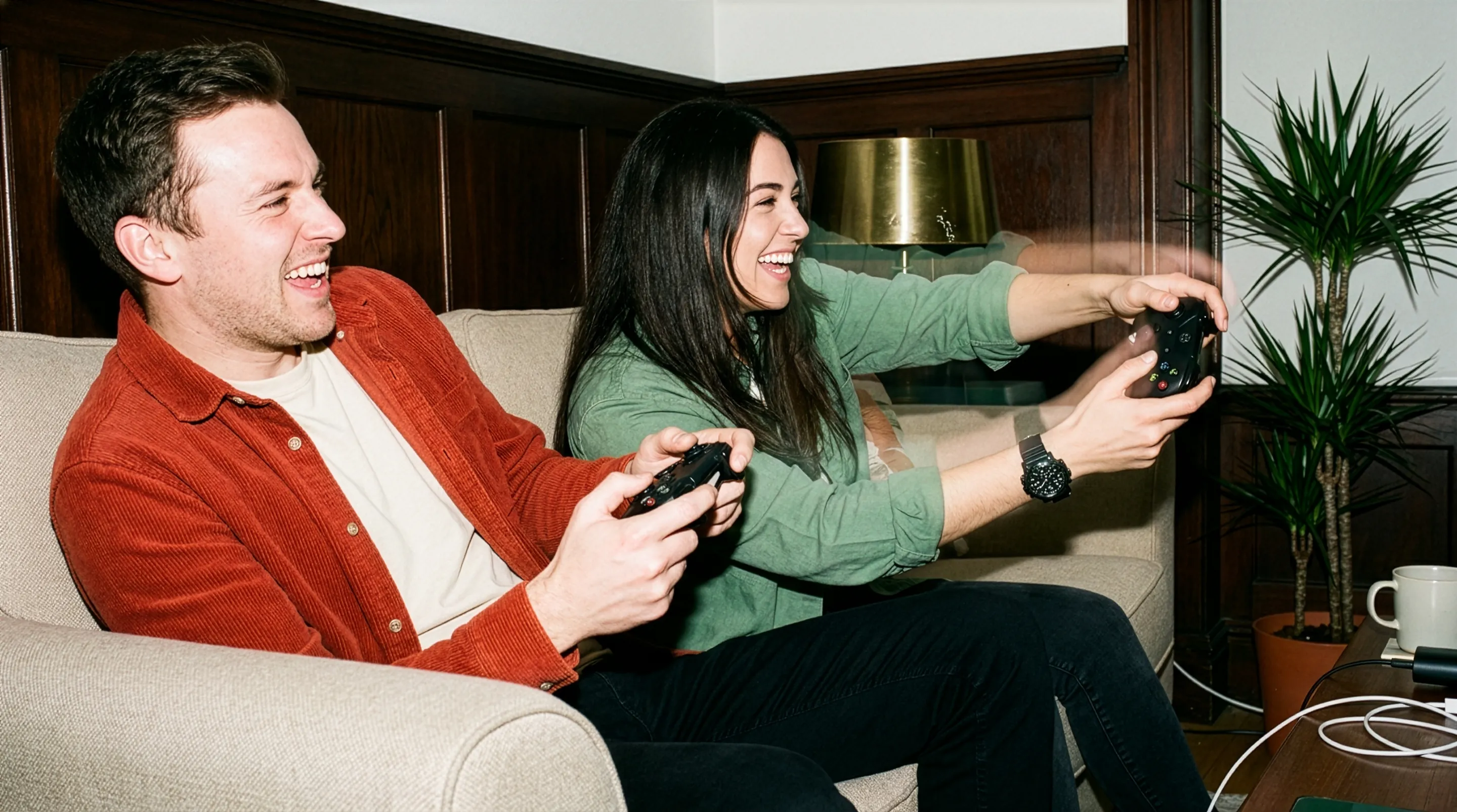 Two friends laughing while playing video games on a couch