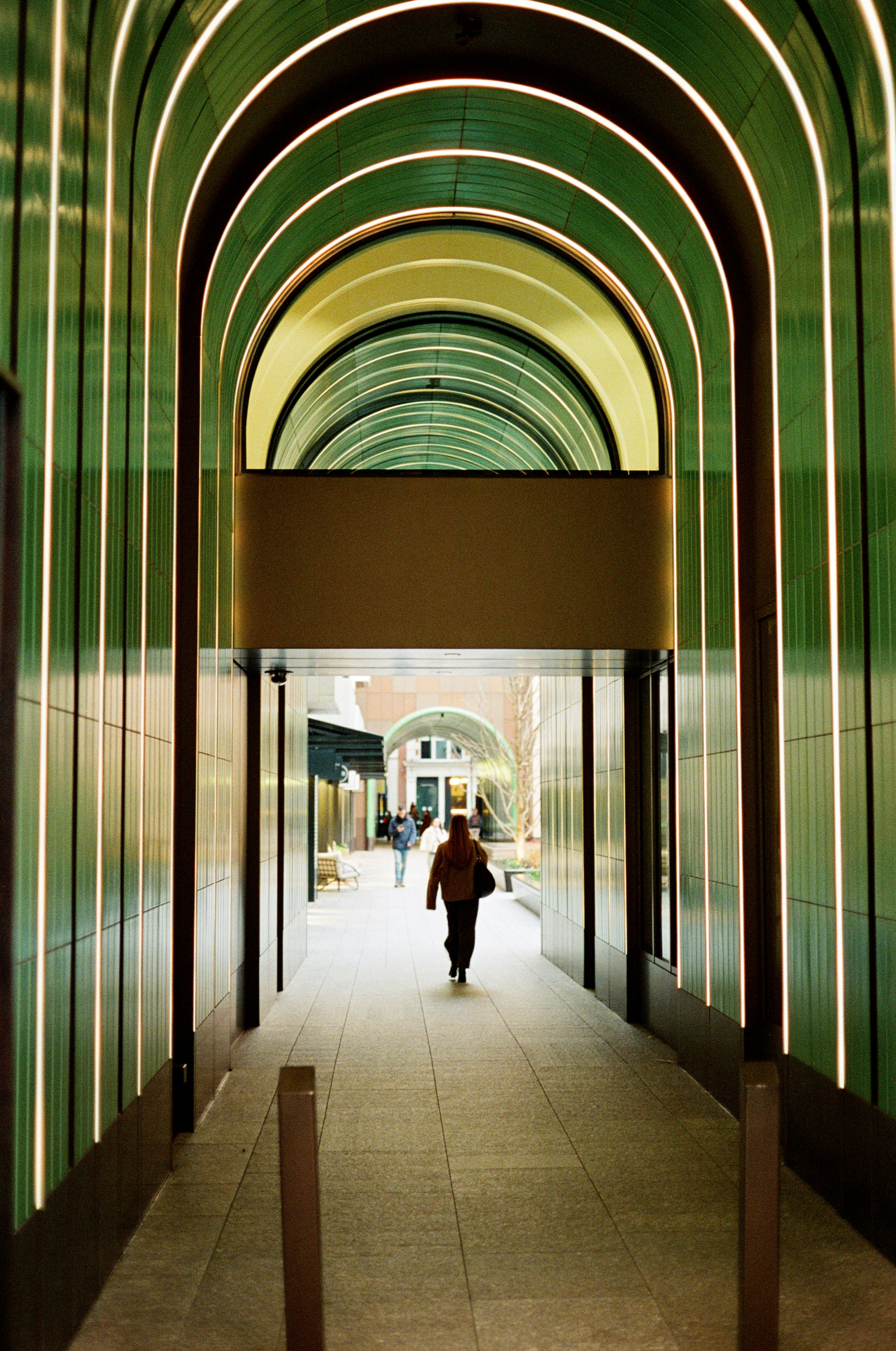 Person walks through a modern green arched walkway.