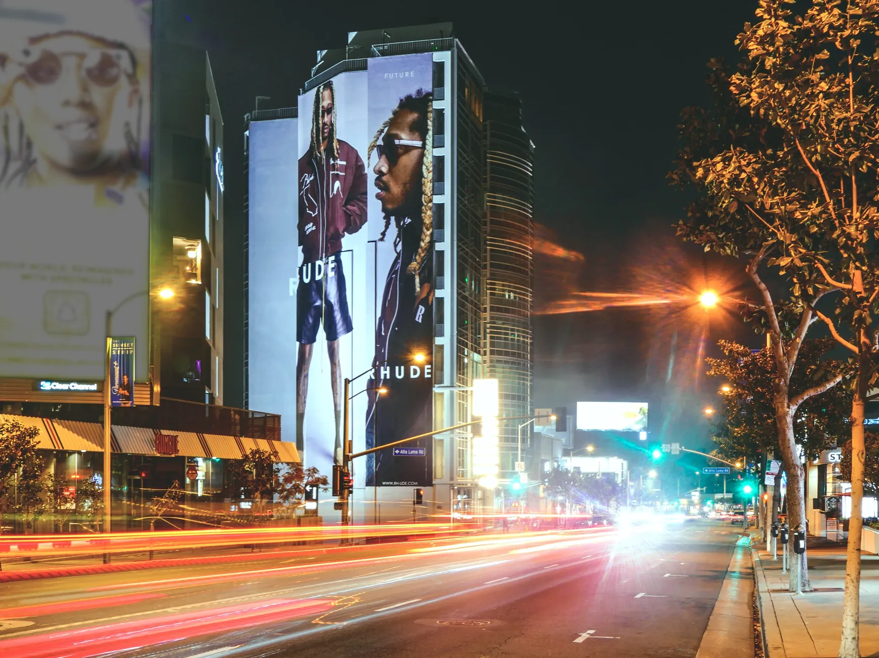 a man walking down a street past a large poster