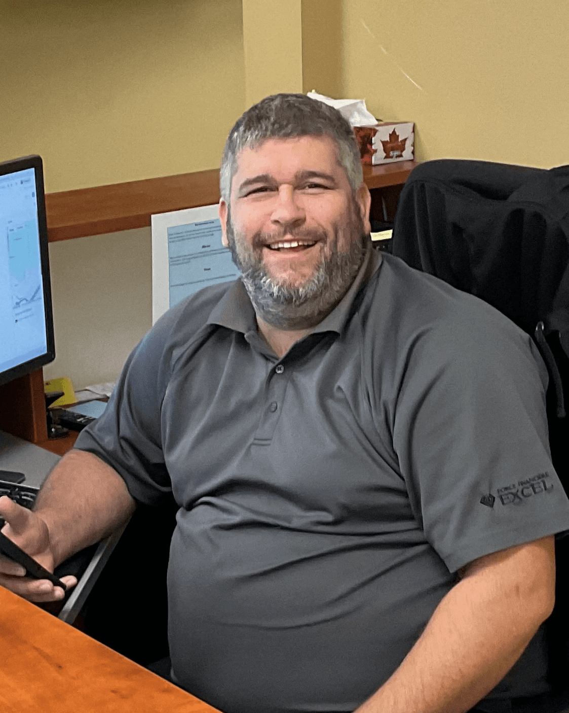 Portrait de Patrick Trudeau, répartiteur, souriant devant son poste de travail.