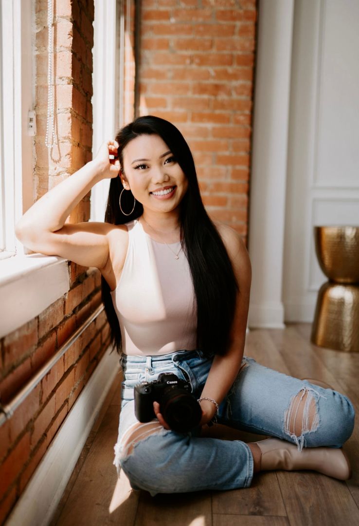 A young woman sitting on the floor holding a camera