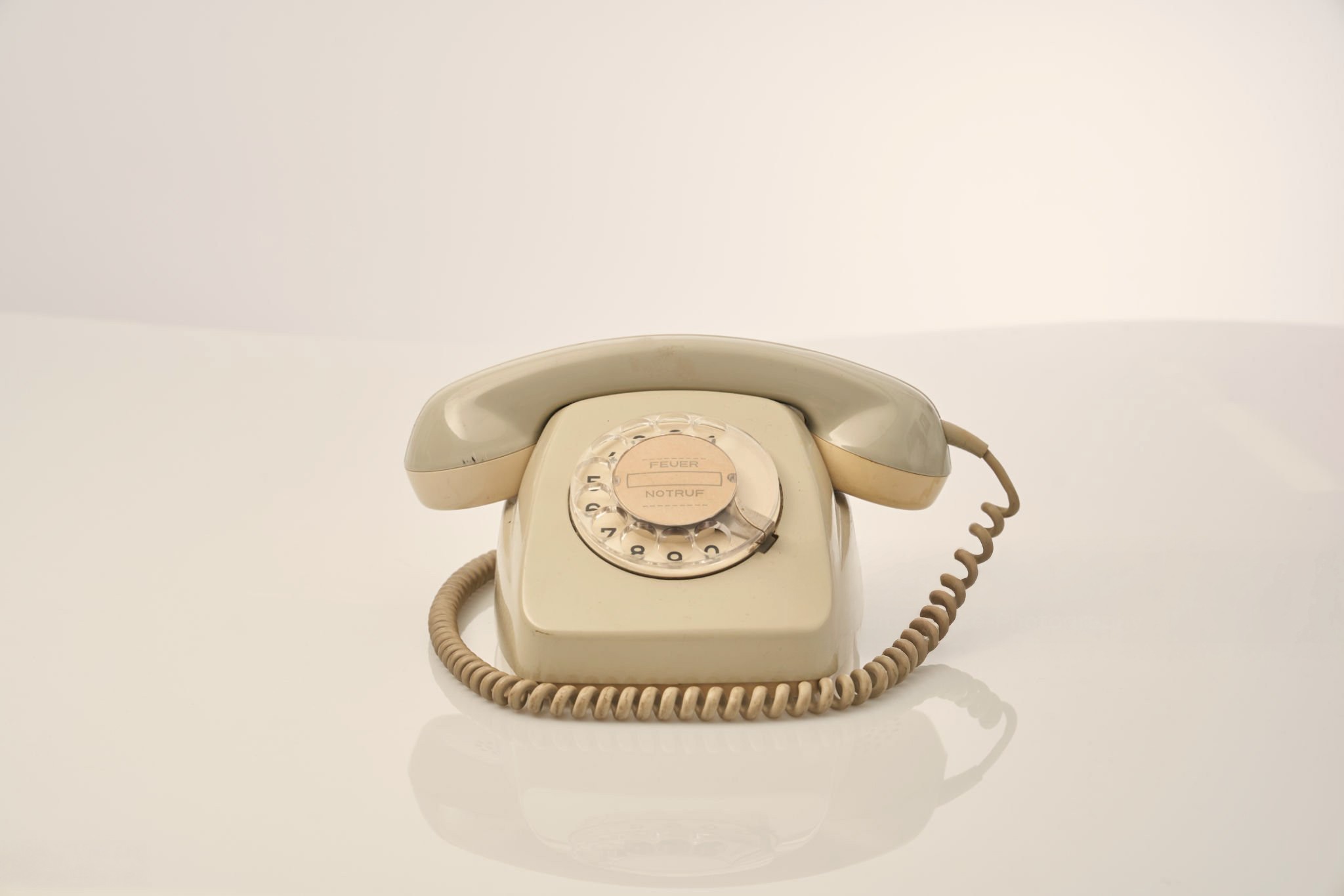 Een kind zit op een bank en aait zachtjes een zwarte hond in een met zonlicht gevulde kamer.