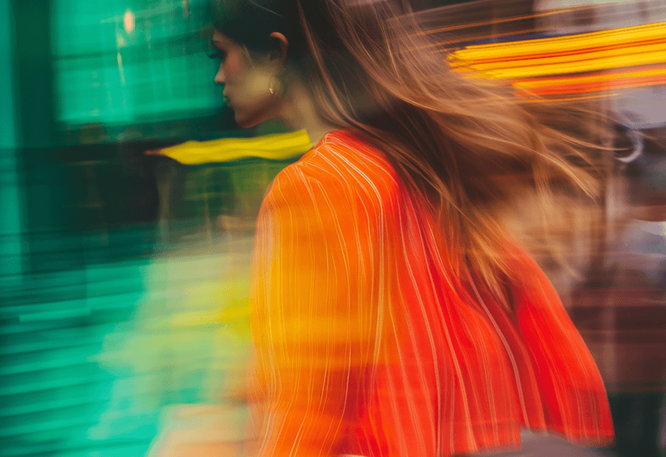 A woman walking down a street, with a blurred background creating a sense of motion and depth.