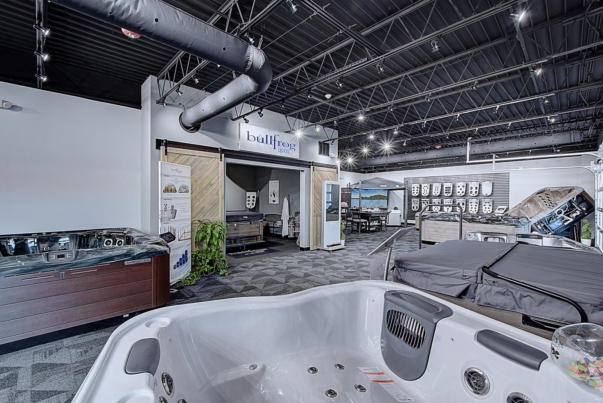 Interior of a modern showroom displaying hot tubs, with sleek decor and spacious layout.