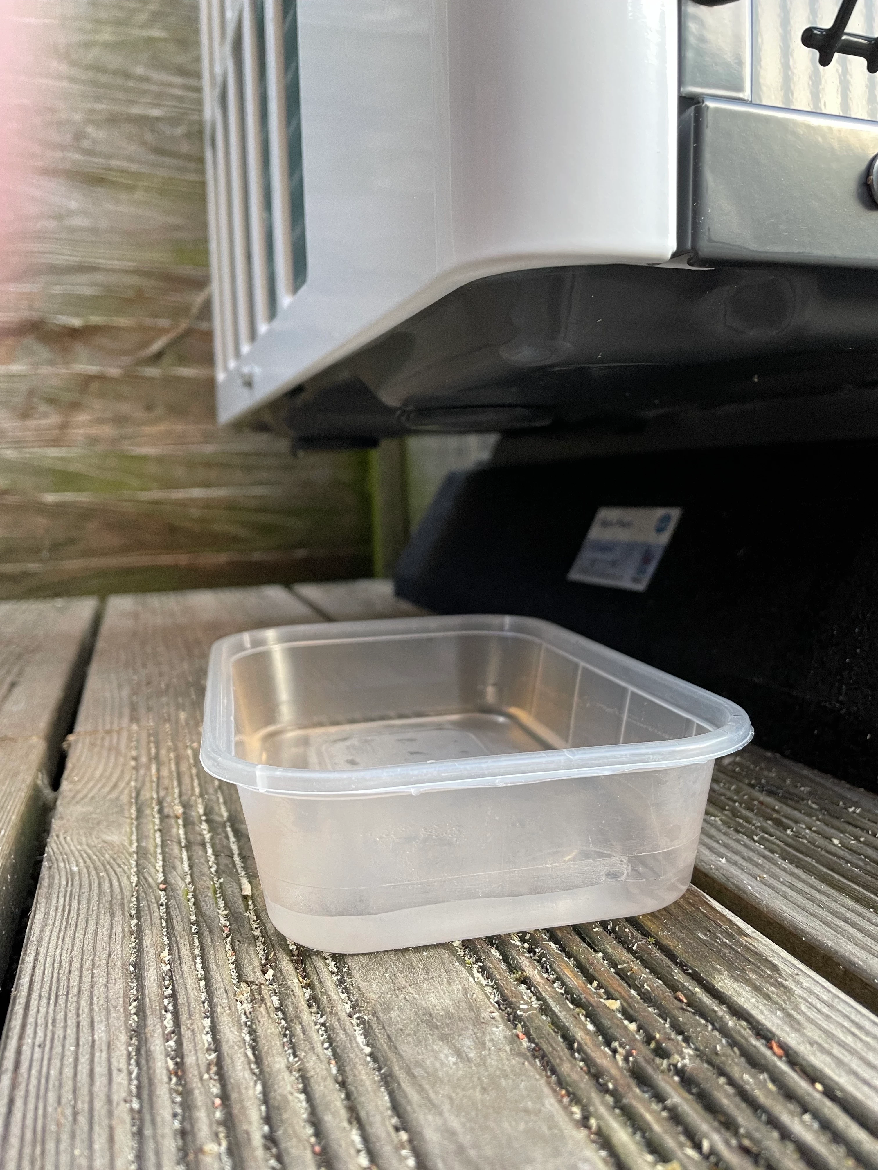 Air source heat pump outdoor unit with condensate water collection tray beneath it — correct drainage prevents freezing and ice hazards around the unit base