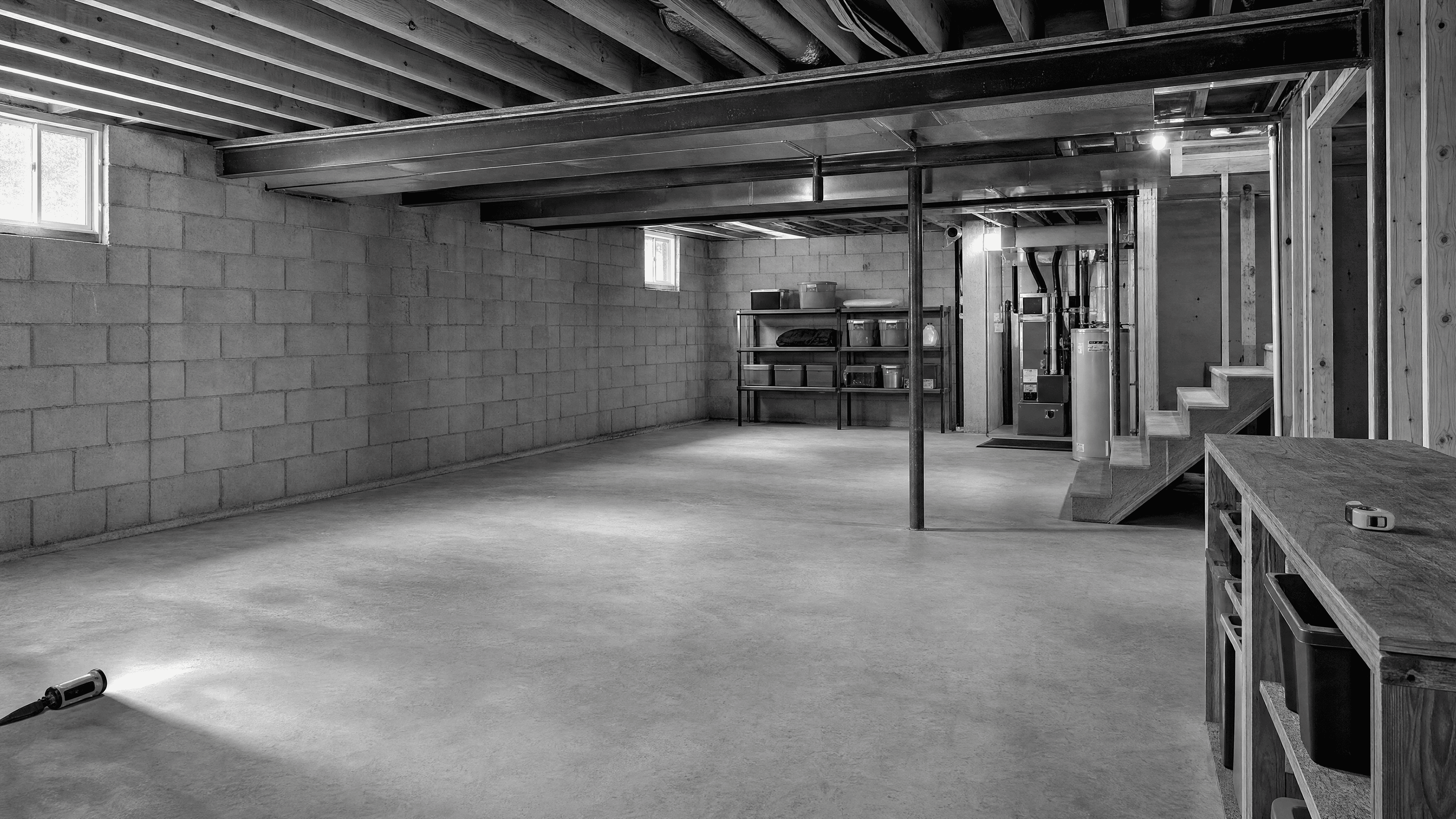 Clean, dry unfinished basement with concrete-block foundation walls, exposed framing, utilities, and open floor space.