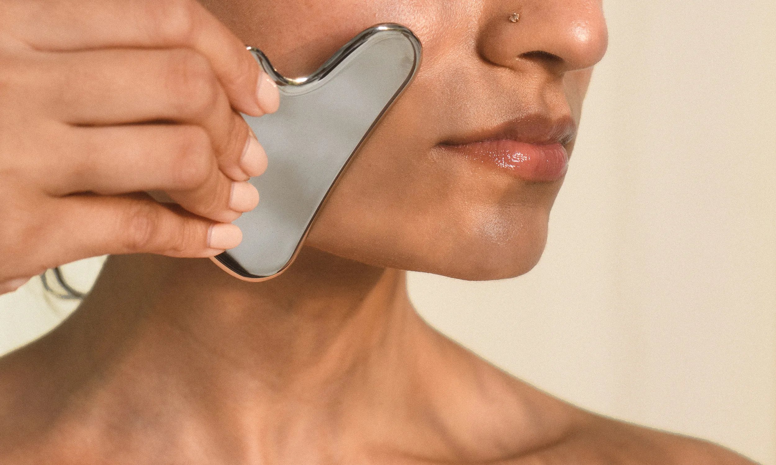 A woman receiving a gua sha facial along her jawline