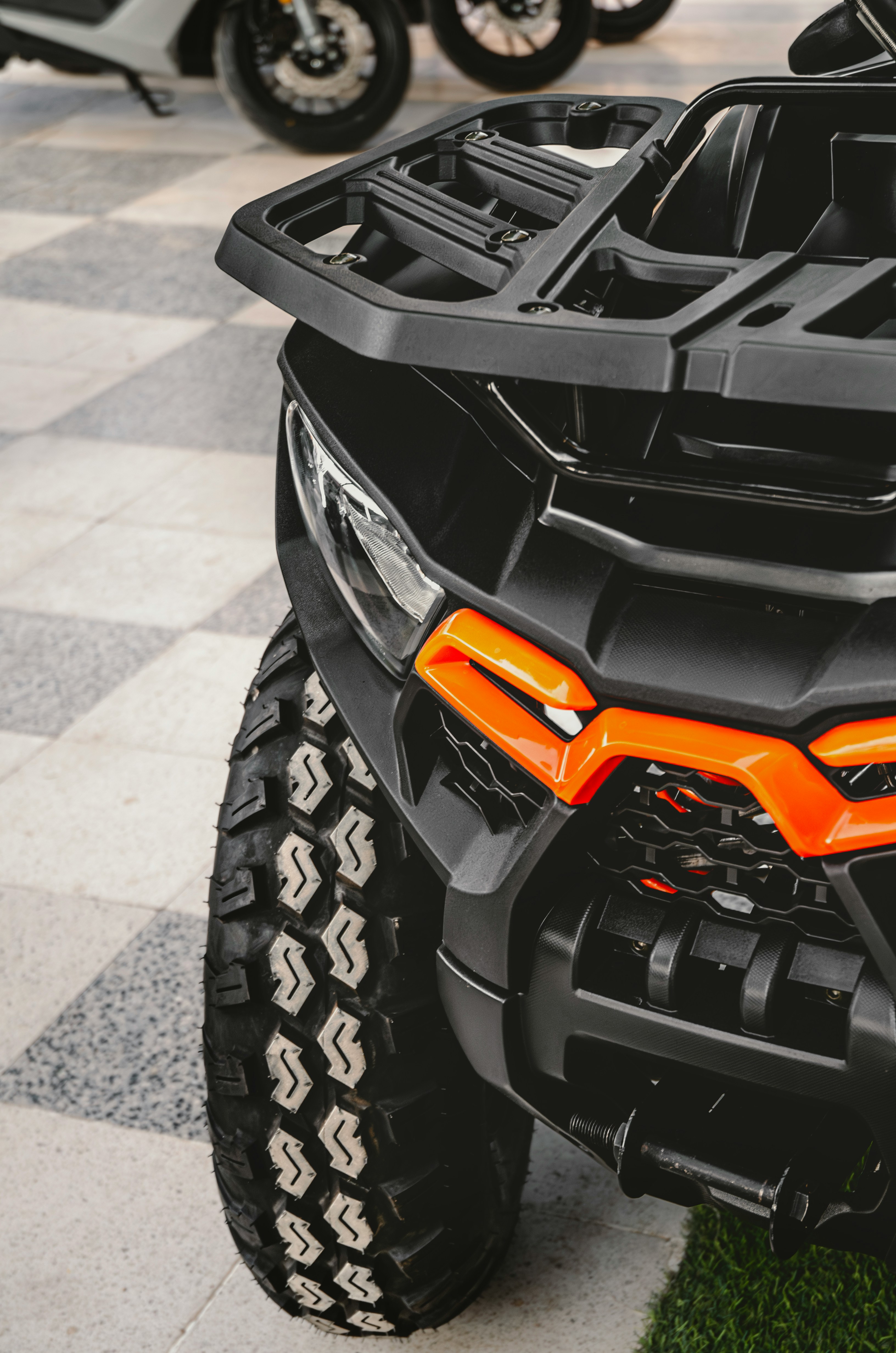 Black ATV front with orange accents and knobby tire