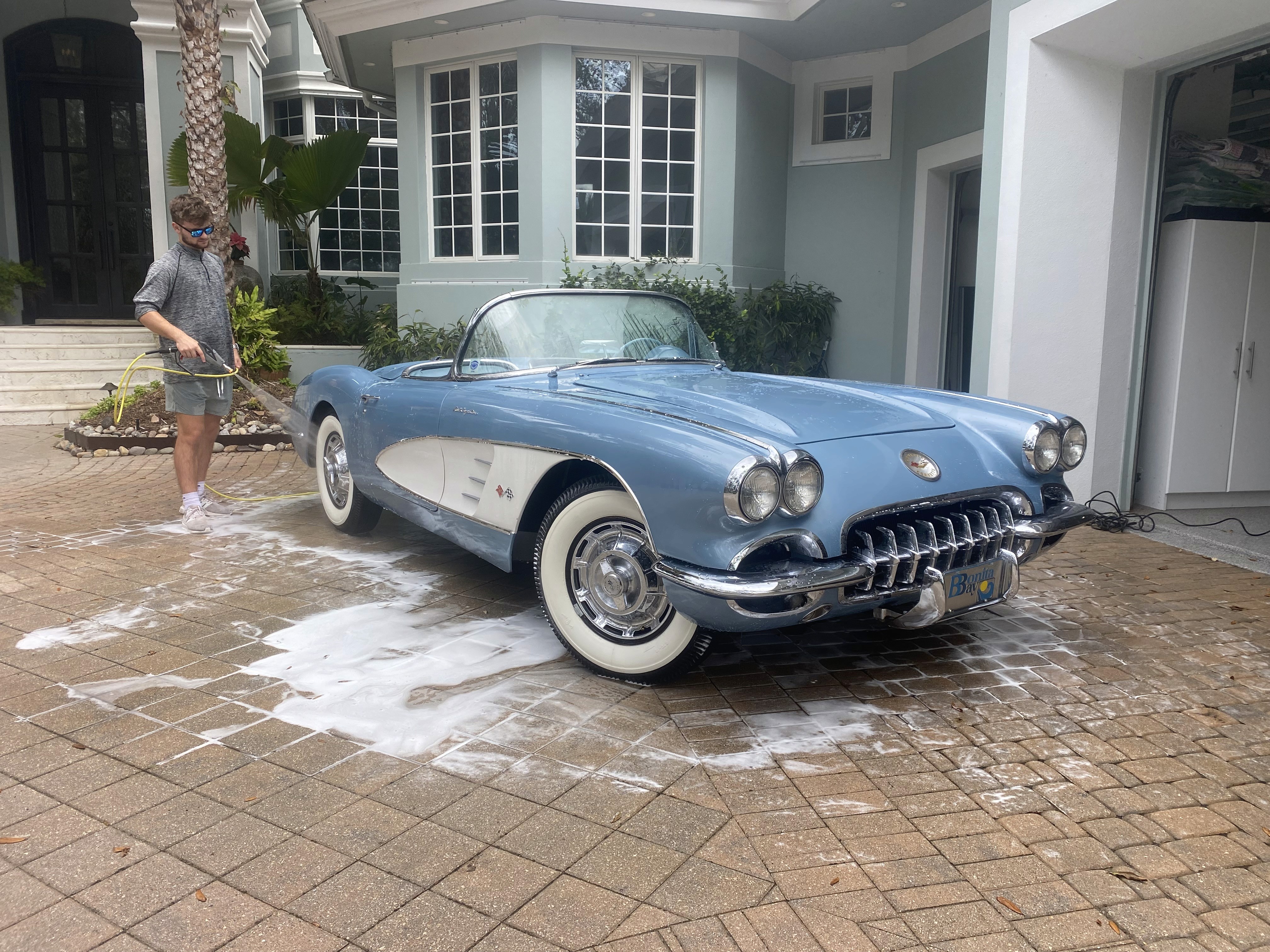 Vintage corvette 1978  with a custom white, blue, and sky blue paint job, freshly detailed with a shiny finish, parked near palm trees on a clear day in Southwest Florida.