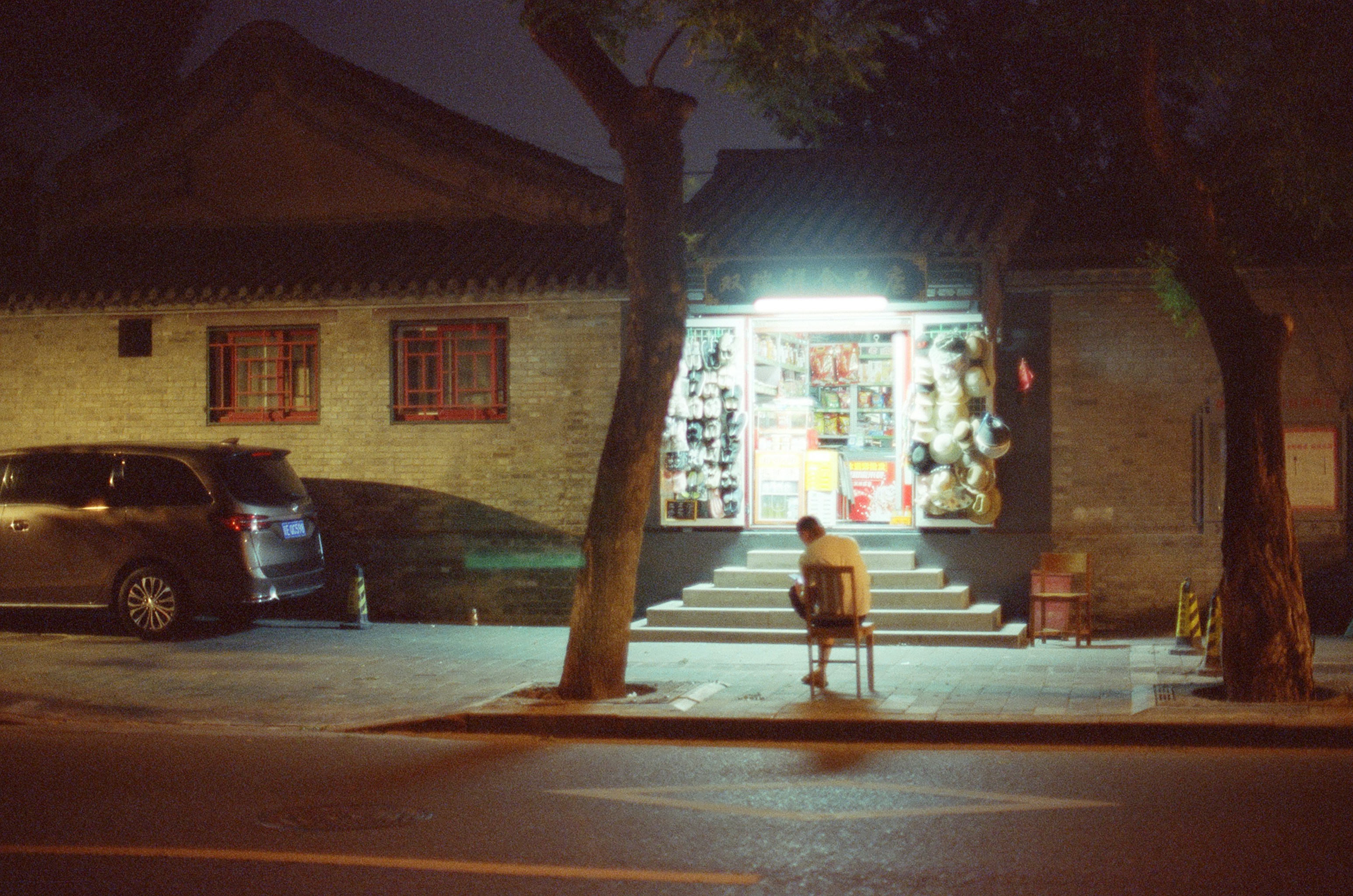 A quiet neighborhood street at night with a lit doorway