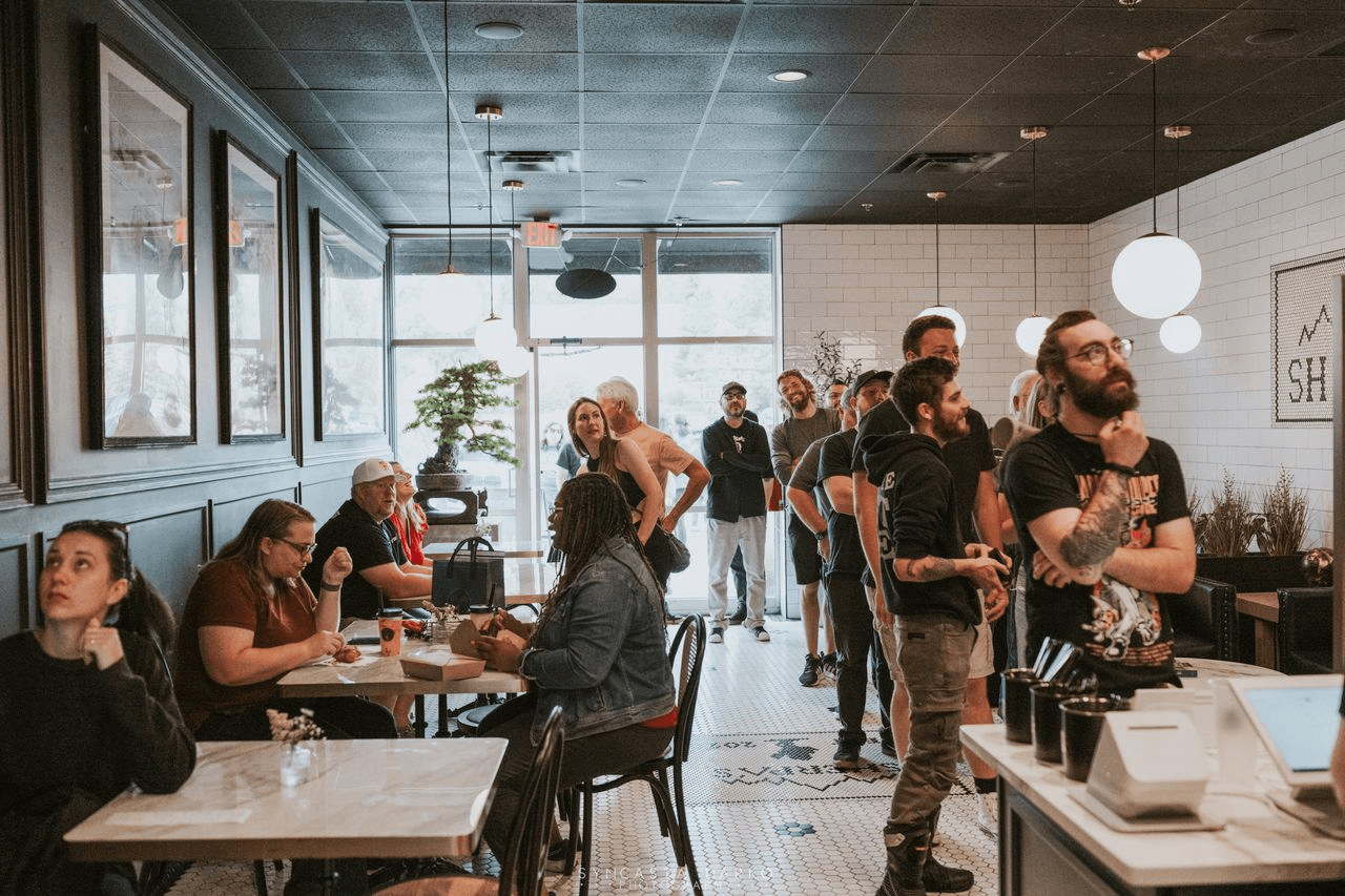 Guests lining up and dining inside Café Sherpa's in Brookfield, WI on a busy day. A lively, welcoming café serving globally inspired drinks and freshly baked goods made in-house every day.