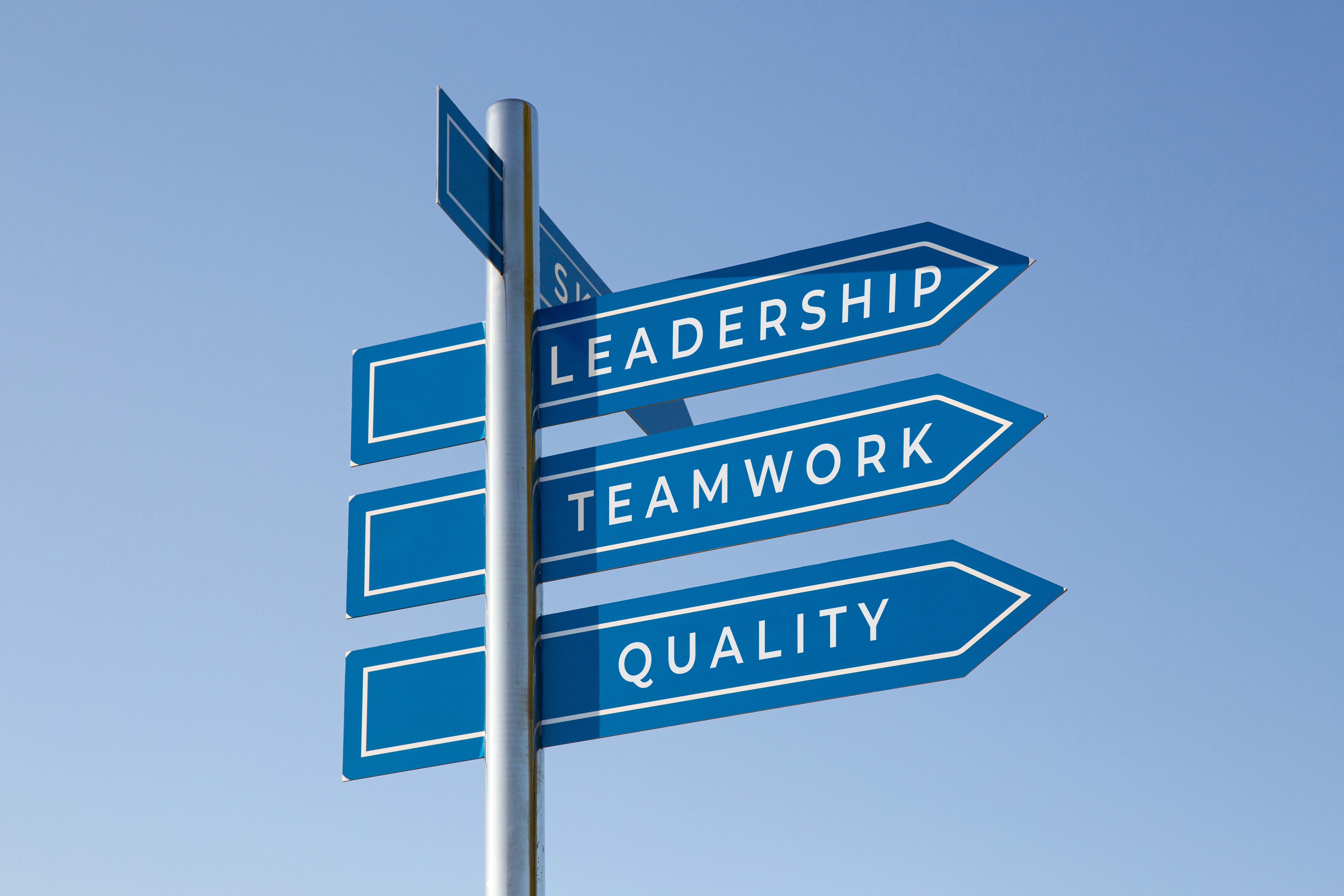 Directional signpost with words Leadership, Teamwork, and Quality representing core values of successful project management and team collaboration
