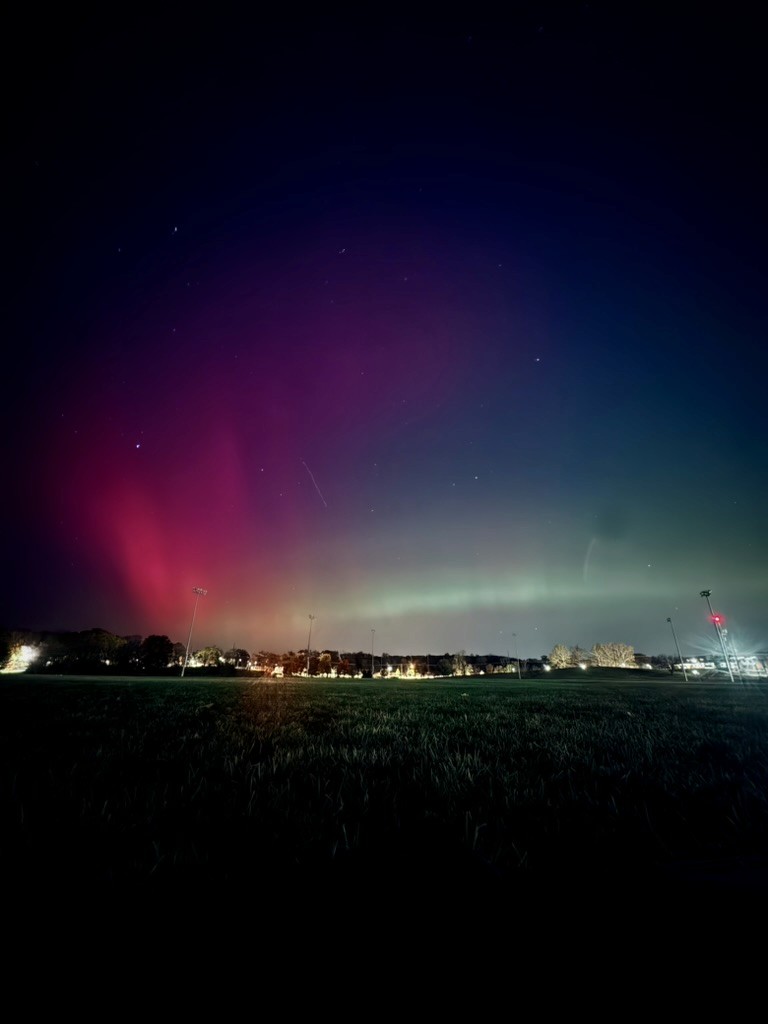 An aurora sky over a grassy field