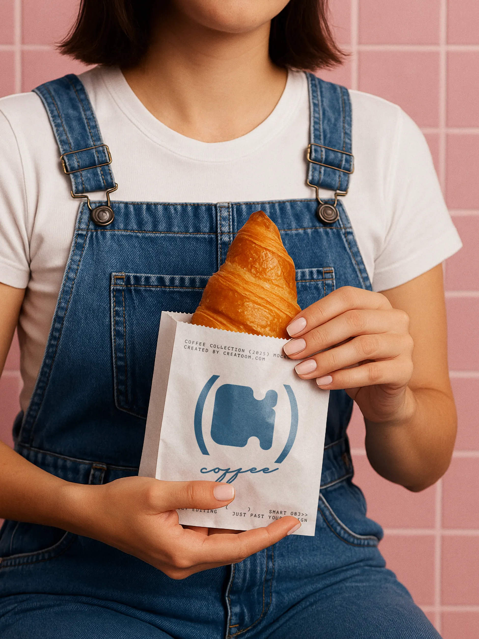 Croissant served in branded pastry sleeve held by person in overalls
