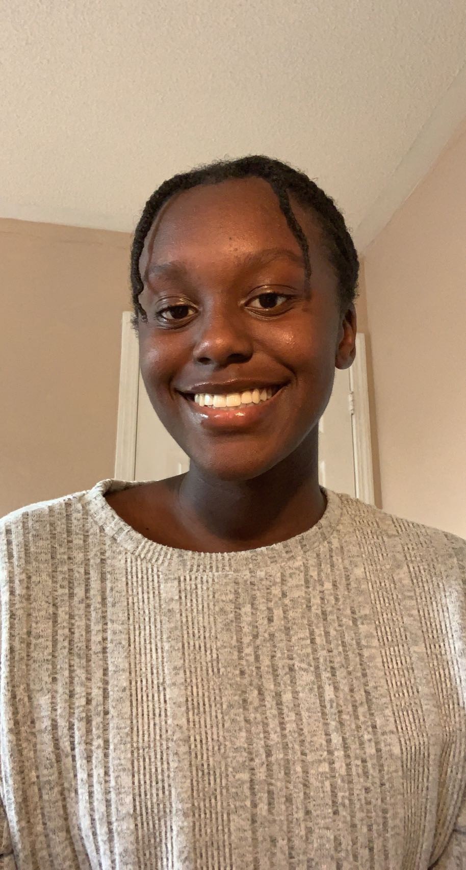 A woman smiling in front of a wall.