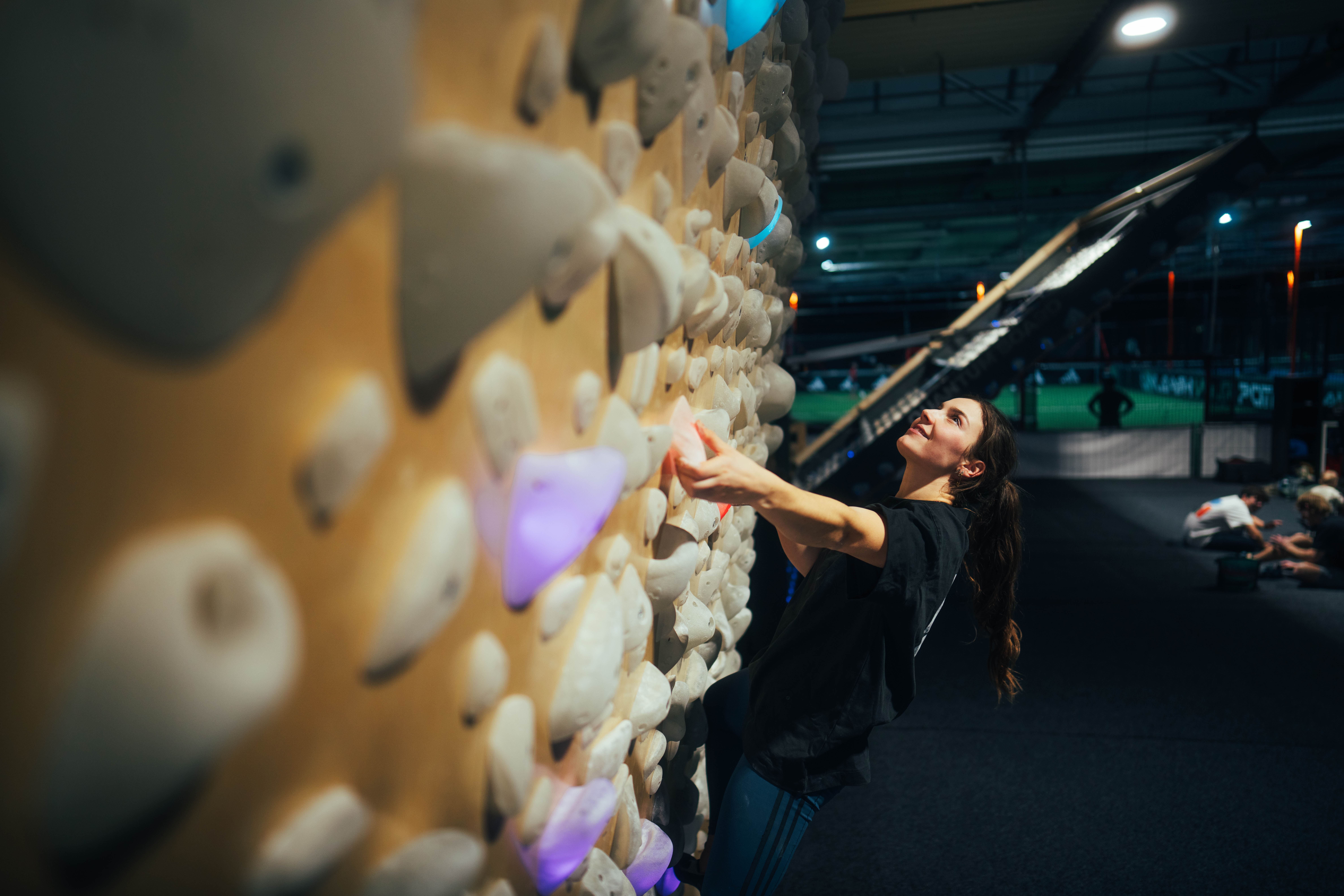 Hand greift einen leuchtenden Griff an der Shiny Wall Systemwand – präzise Grifftechnik beim Indoor-Bouldern im The Boulder Room München.