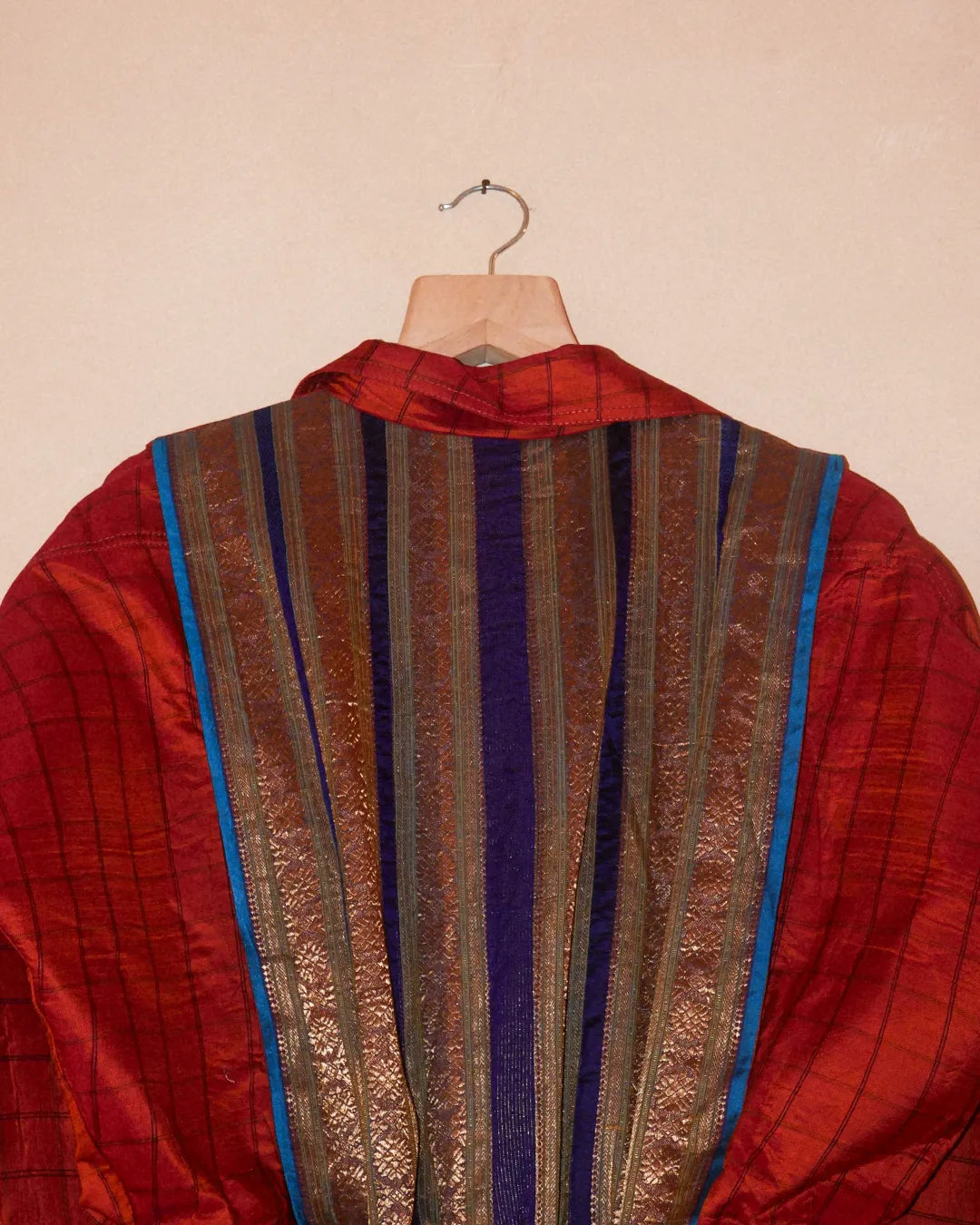 AMBR is our one-of-a-kind cropped two-toned silk brocade bomber jacket, handcrafted by skilled artisans in-house using a vintage silk saris. The back panel features a rich brocade. In our effort to use what already exists, both layers are crafted entirely from vintage textiles. With an exaggerated collar, a slight cinch at the waist, and antique buttons, Ambr stands as a tribute to local craftsmanship and mindful creation.