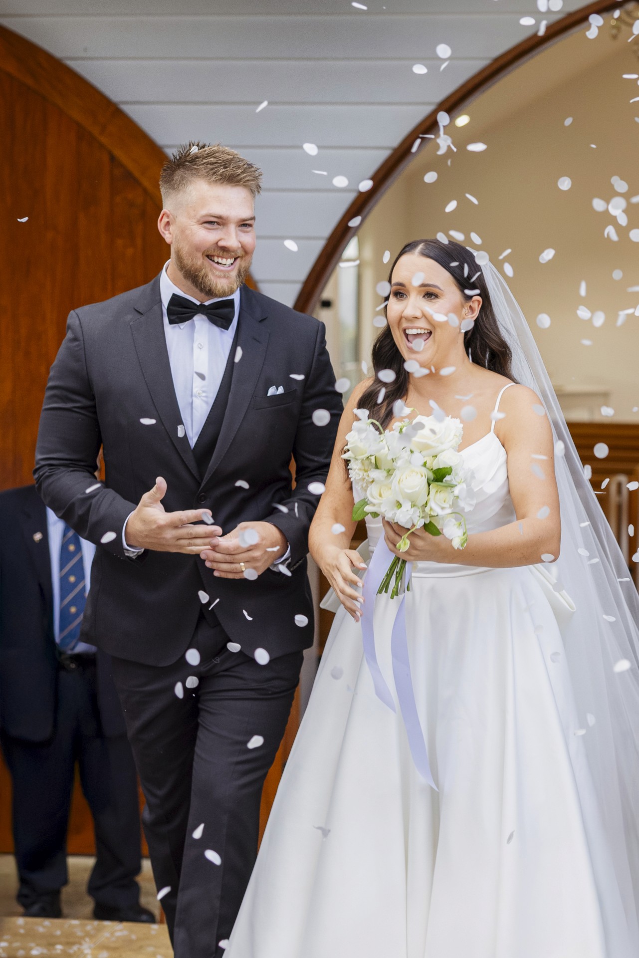 Bride and groom walking out of church through confetti