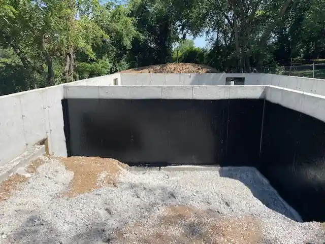 Rub-R-Proof black ashphalt waterproof coating sprayed onto the foundation of a new residential build