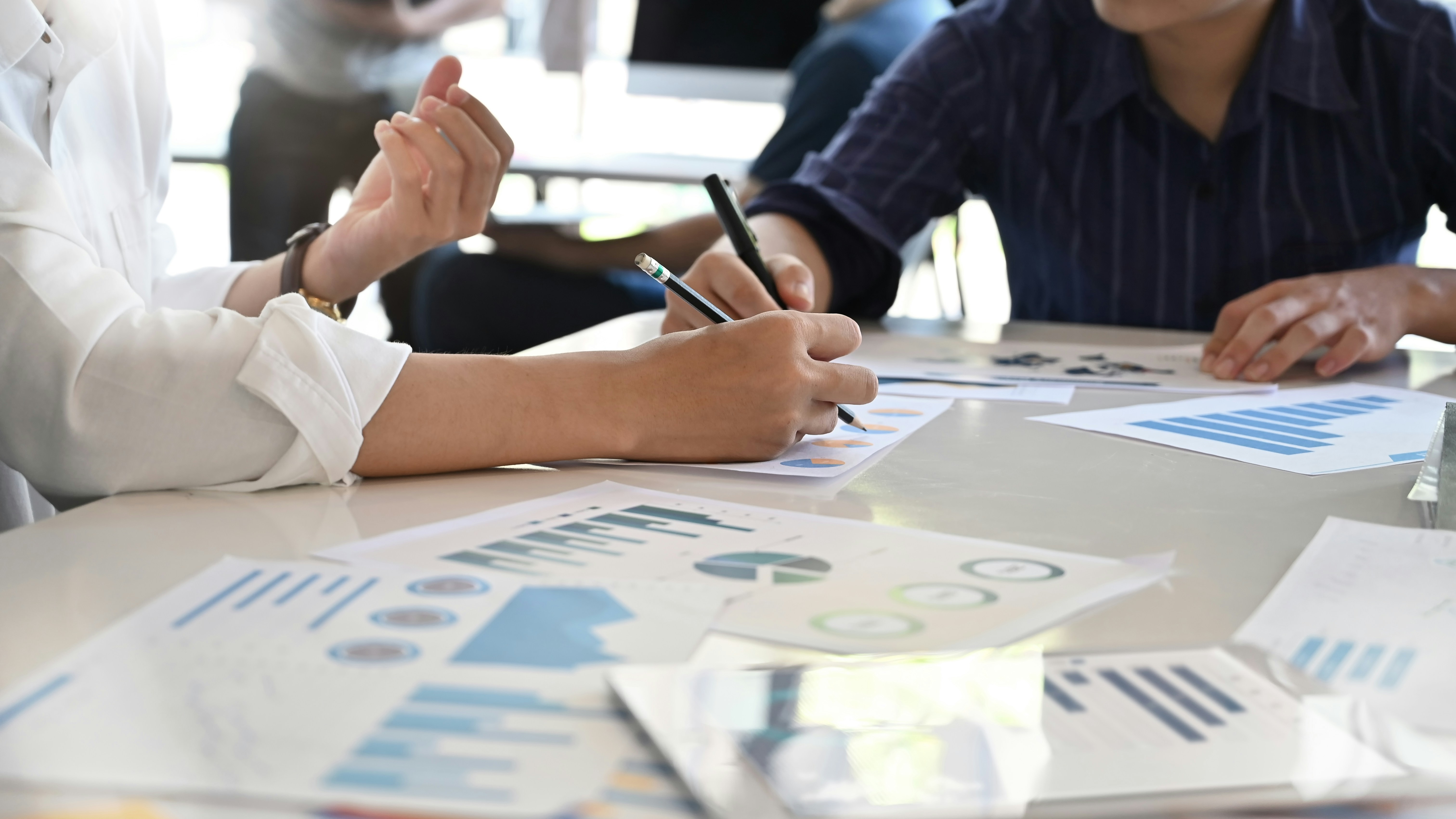 Close-up of participants collaborating during the Expert Pool Session on Fundraising for Ukrainian communities, with hands pointing at financial charts and documents.