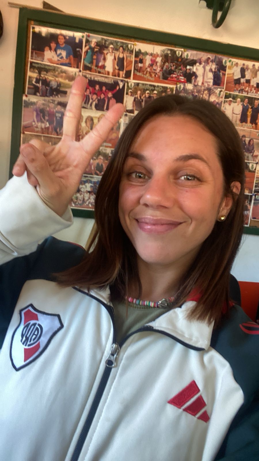 Smiling man wearing glasses and a grey shirt standing with folded arms against a neutral background.