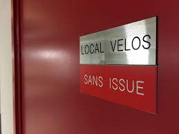 Signalétique Interne argentée indiquant « Local Velos » et une enseigne rouge en dessous indiquant « Sans Issue », signifiant qu'il n'y a pas de sortie. Design minimaliste, ton fonctionnel.
