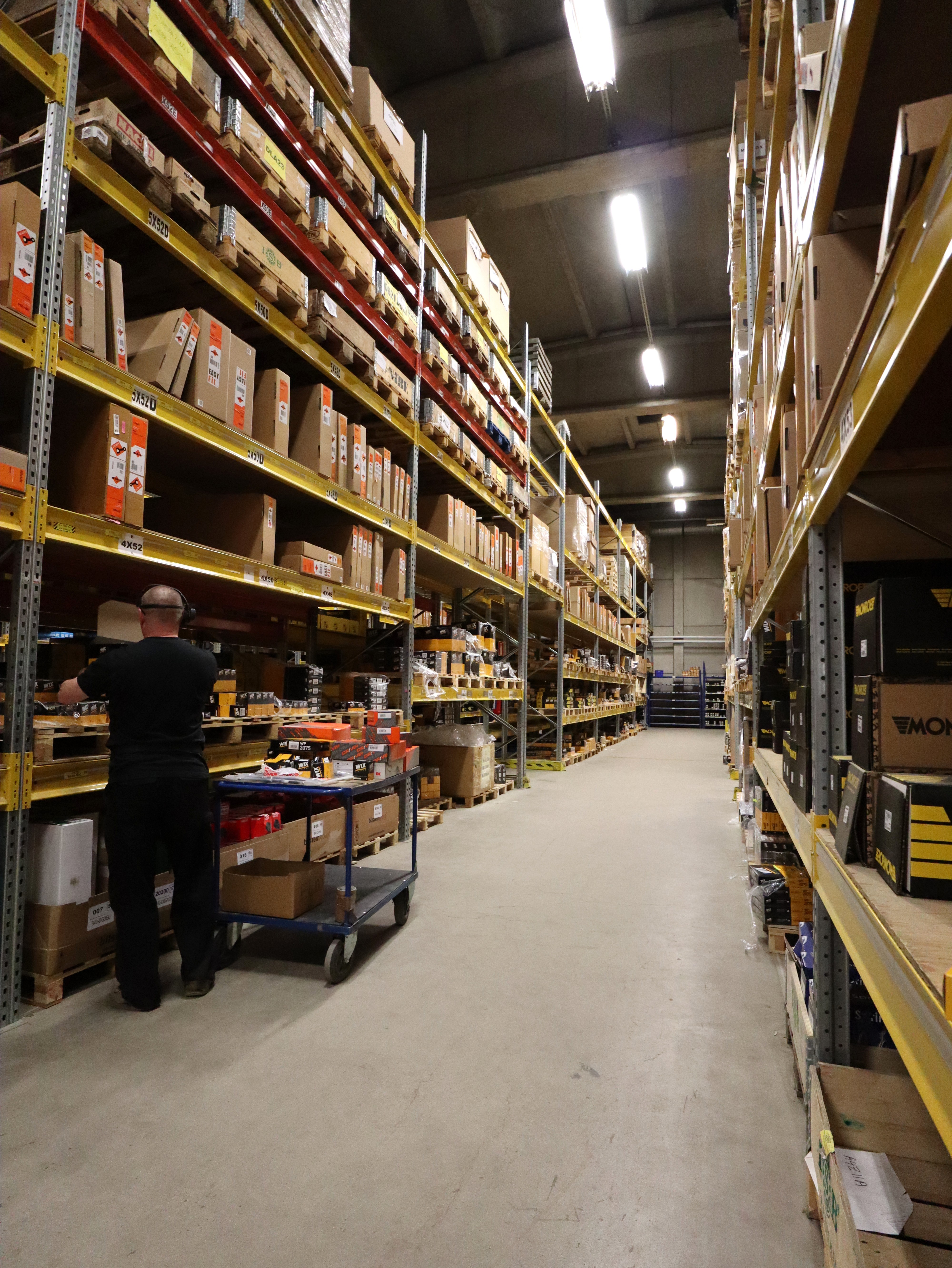 Warehouse worker organizing shelves stacked with boxes and supplies