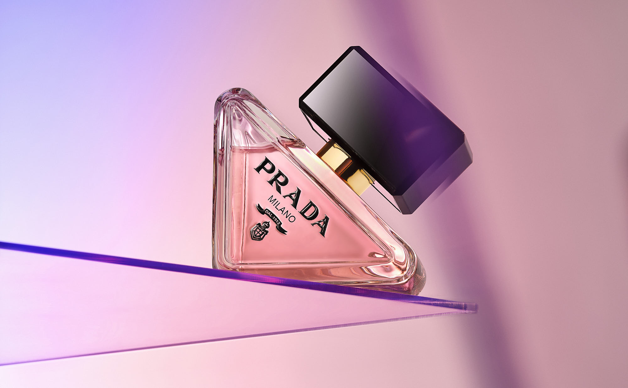 A stylish perfume bottle with a sleek black cap, set against a soft pink and purple gradient background.