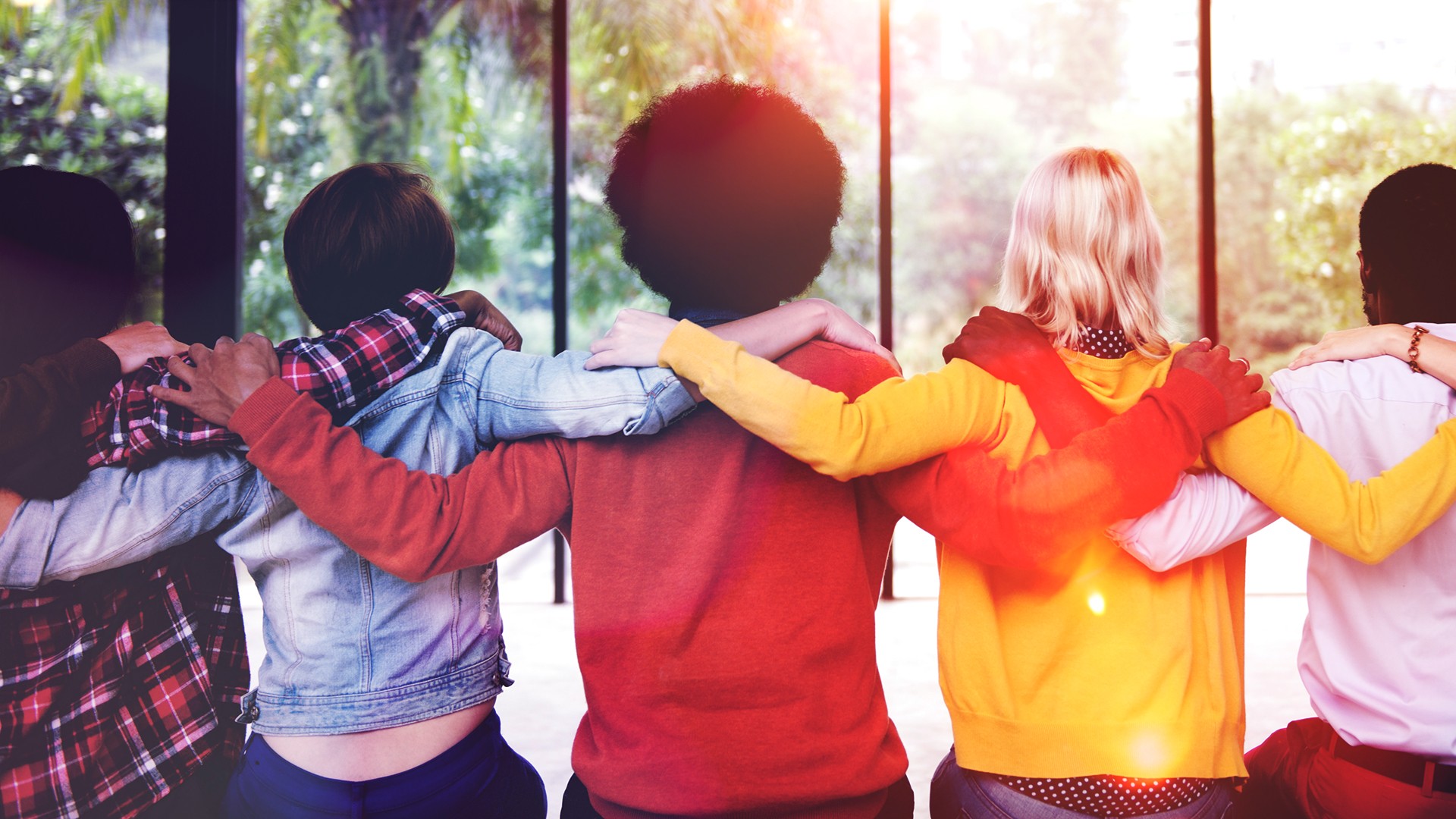 Three people facing away from the camera, arms over each others shoulders