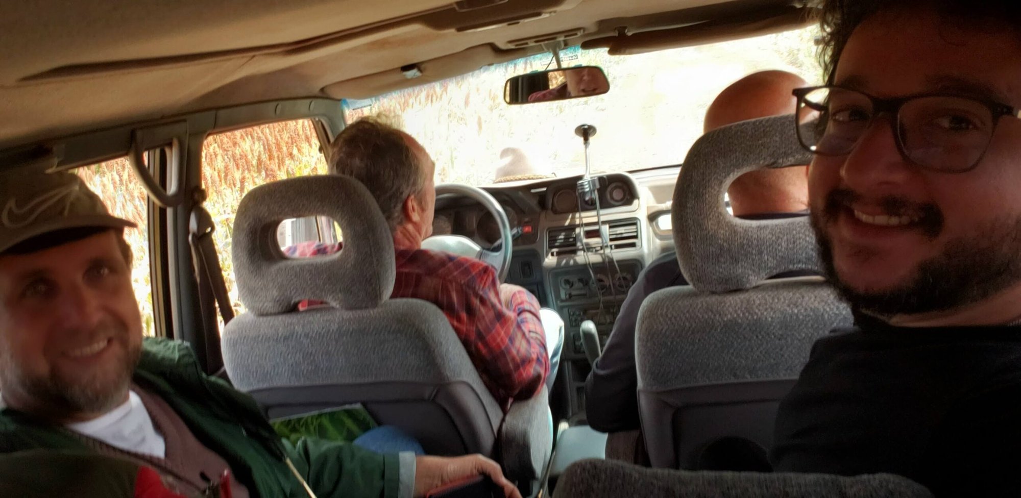 Homens sorrindo dentro de um carro durante deslocamento entre as áreas visitadas