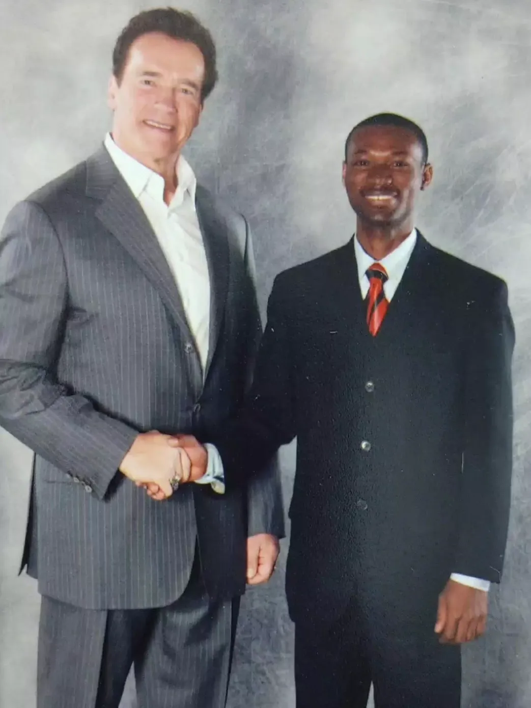 A picture of the founder, Dr. Charles Jhessim, with popular movie actor, Arnold Schwarzenegger