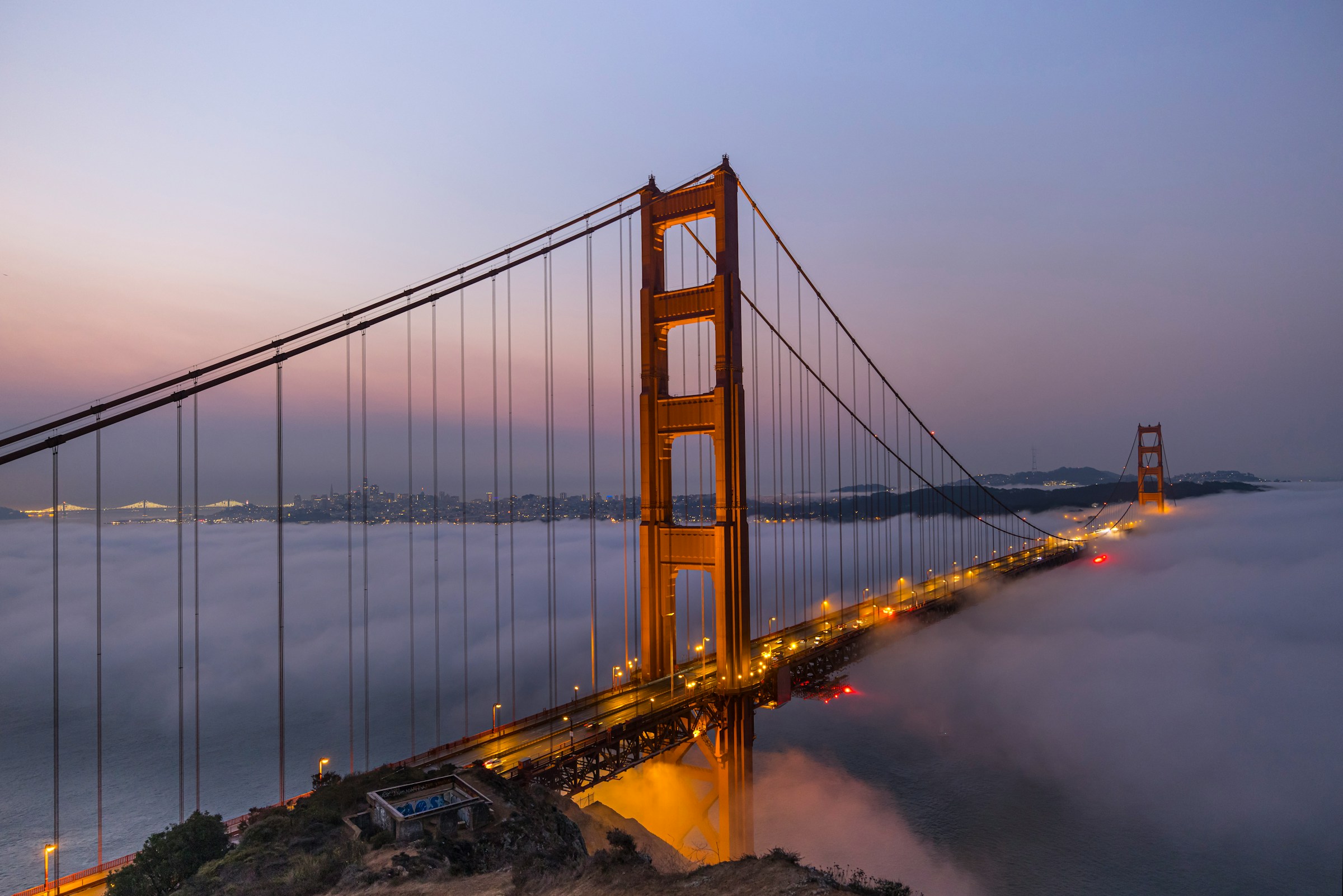 The Golden Gate Bridge at dusk with fog rolling beneath it