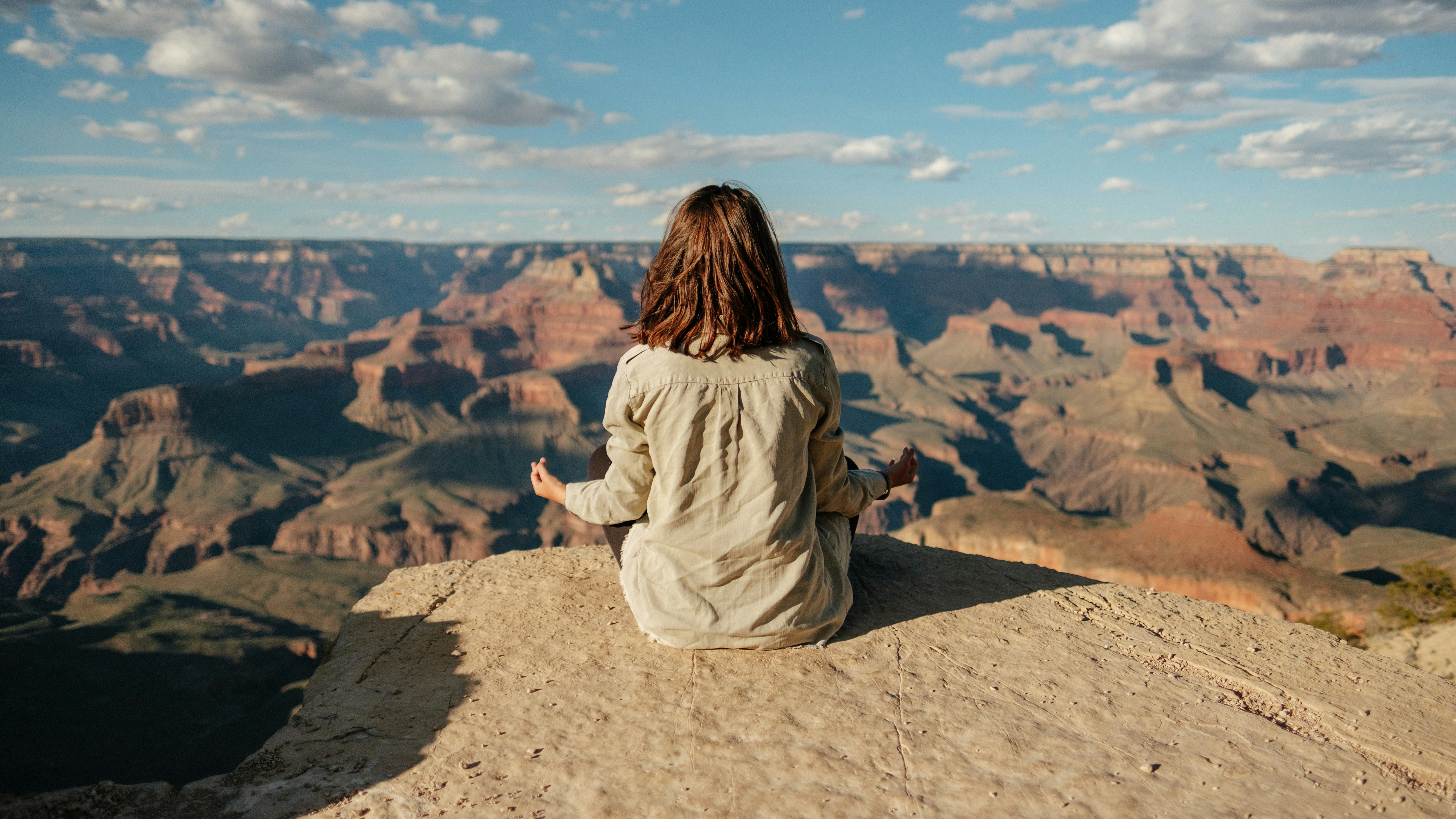 woman on top of a mountain meditating looking towards the horizon