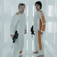 Two prijsoners wearing white and orange jumpsuits holding blasters in a white prison