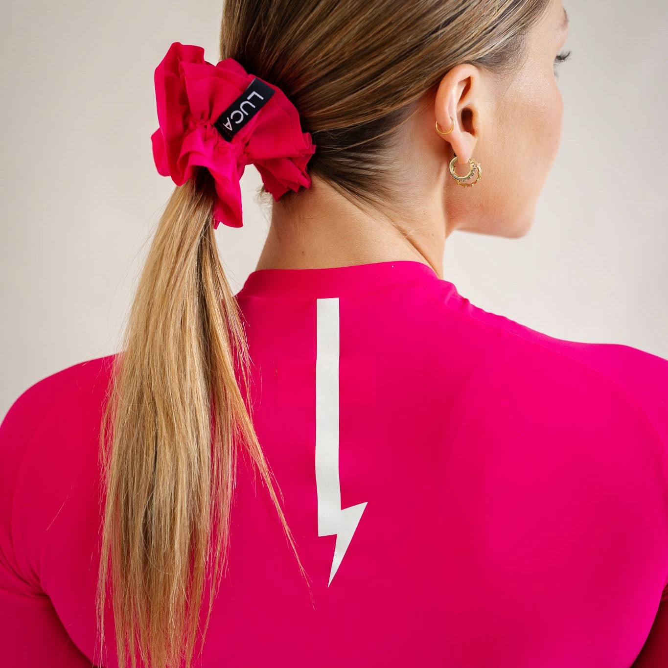 Cyclist wearing LUCA Uplift scrunchie in hibiscus holding a ponytail, back view