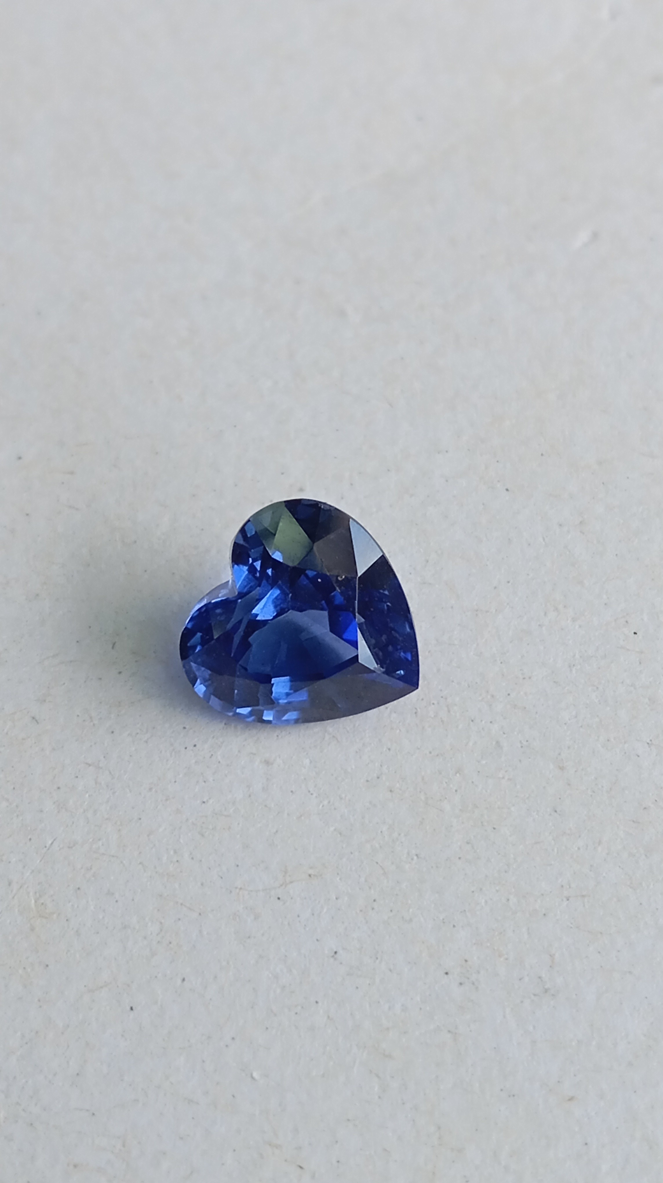 Face-up view of a vivid royal blue heart-shaped lab-grown sapphire loose gemstone.