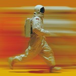 Verschwommenes Bild eines Astronauten beim laufen vor einer kanllig orangenen Wand.