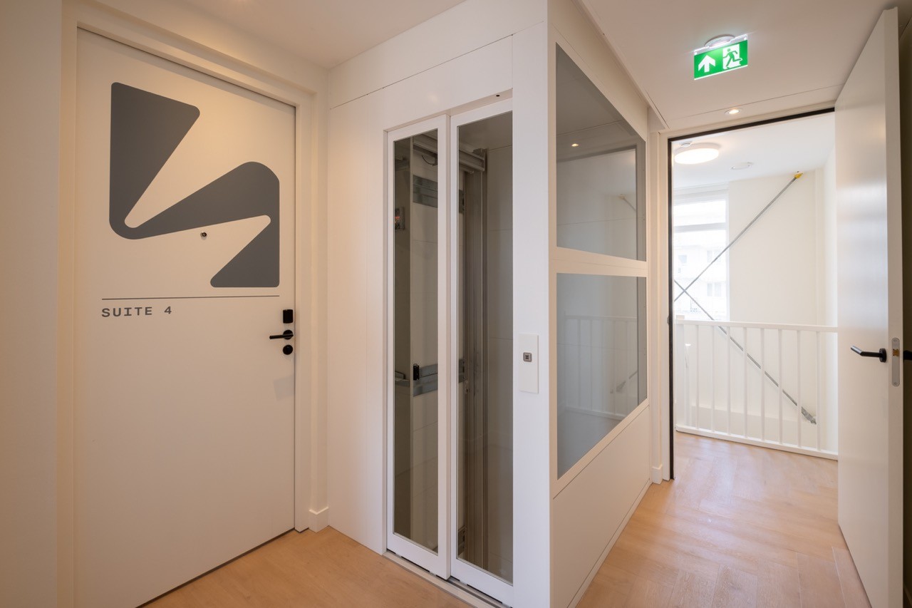 Moderne hotelgang met lift en houten vloer in accommodatie in Scheveningen