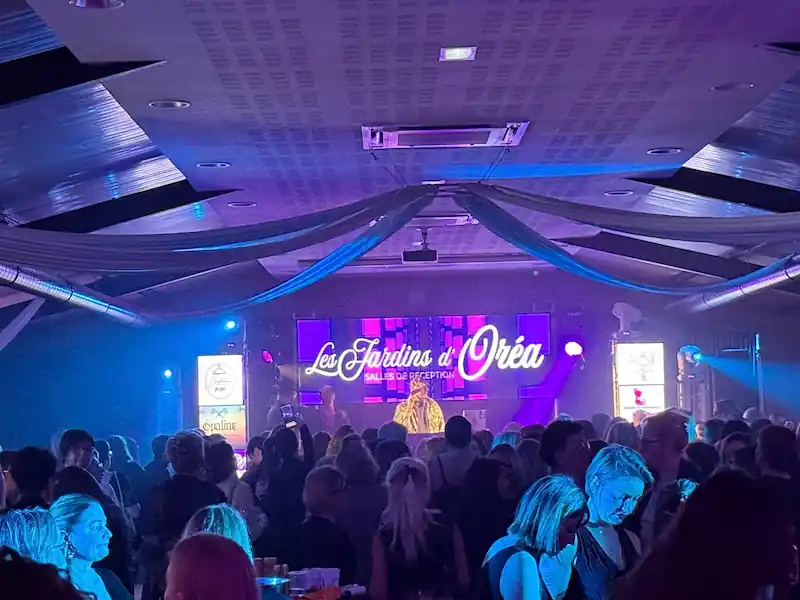 Modern indoor space with large glass doors, lush greenery, and a cozy seating area visible beyond.