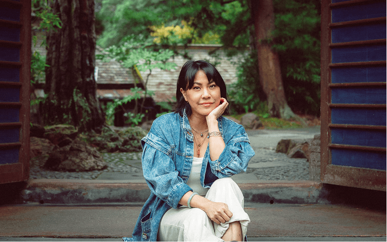 Priscilla Woo sitting outside a garden