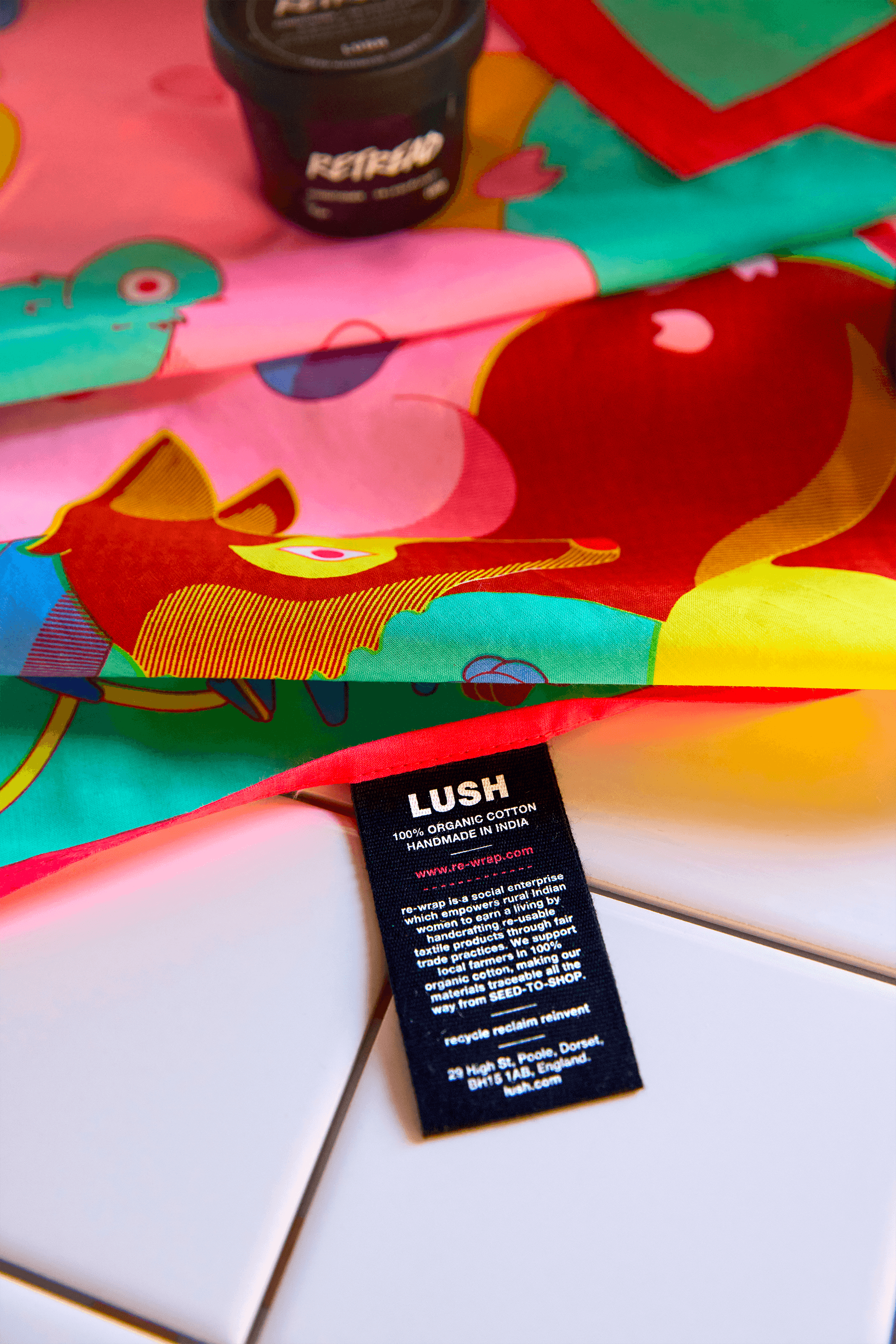 Close-up of colorful illustrated fabric with flowing shapes and a bird motif, showing the Lush fabric label attached.