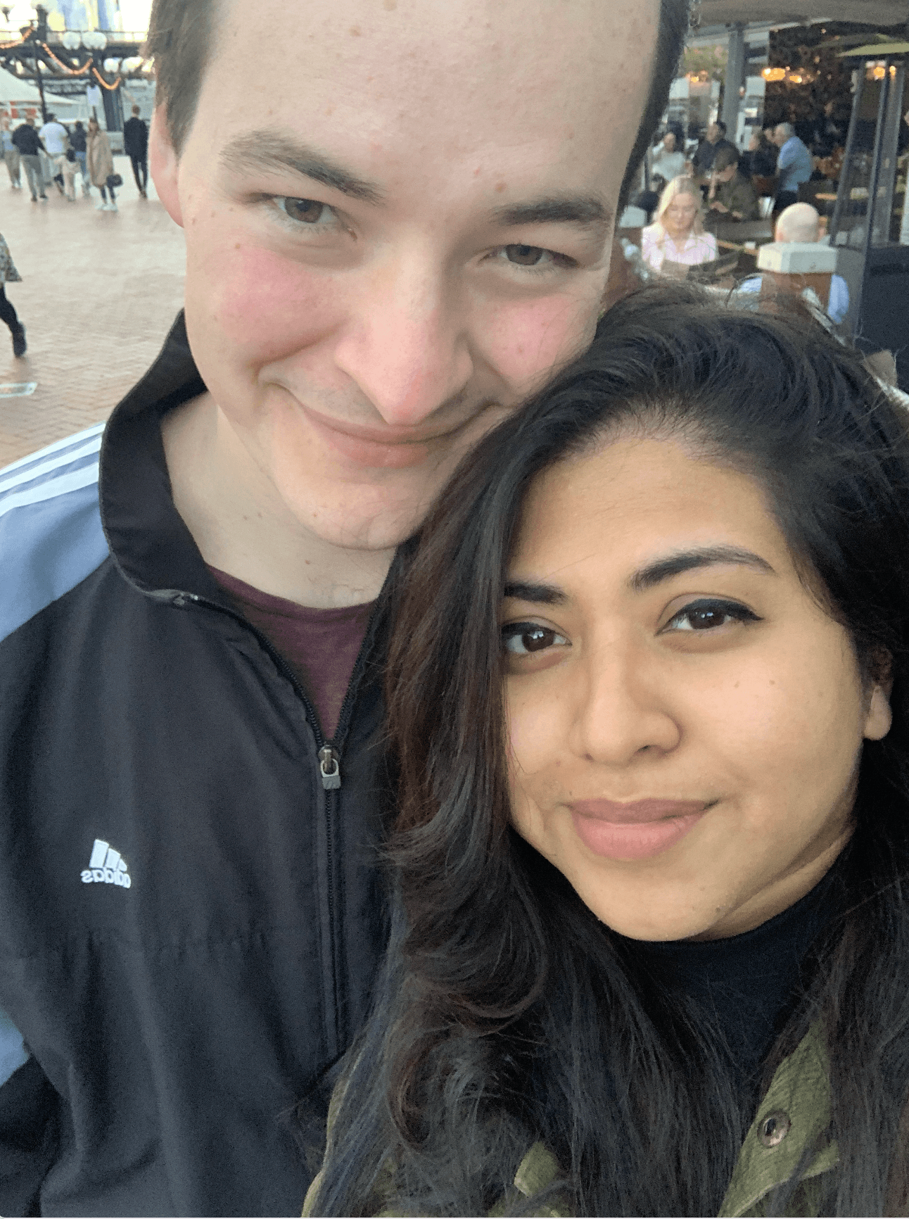 Close-up of two hands gently clasped, one wearing a sparkling engagement ring. The soft lighting and pastel nails evoke a sense of romance and intimacy.