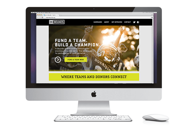 An Apple iMac computer displays a webpage titled "IN BOUNDS" with a banner image featuring a football player in a helmet. The text on the banner reads "FUND A TEAM. BUILD A CHAMPION." Below the banner, a yellow banner contains the text "WHERE TEAMS AND DONORS CONNECT." A white Apple keyboard and mouse are positioned in front of the computer.