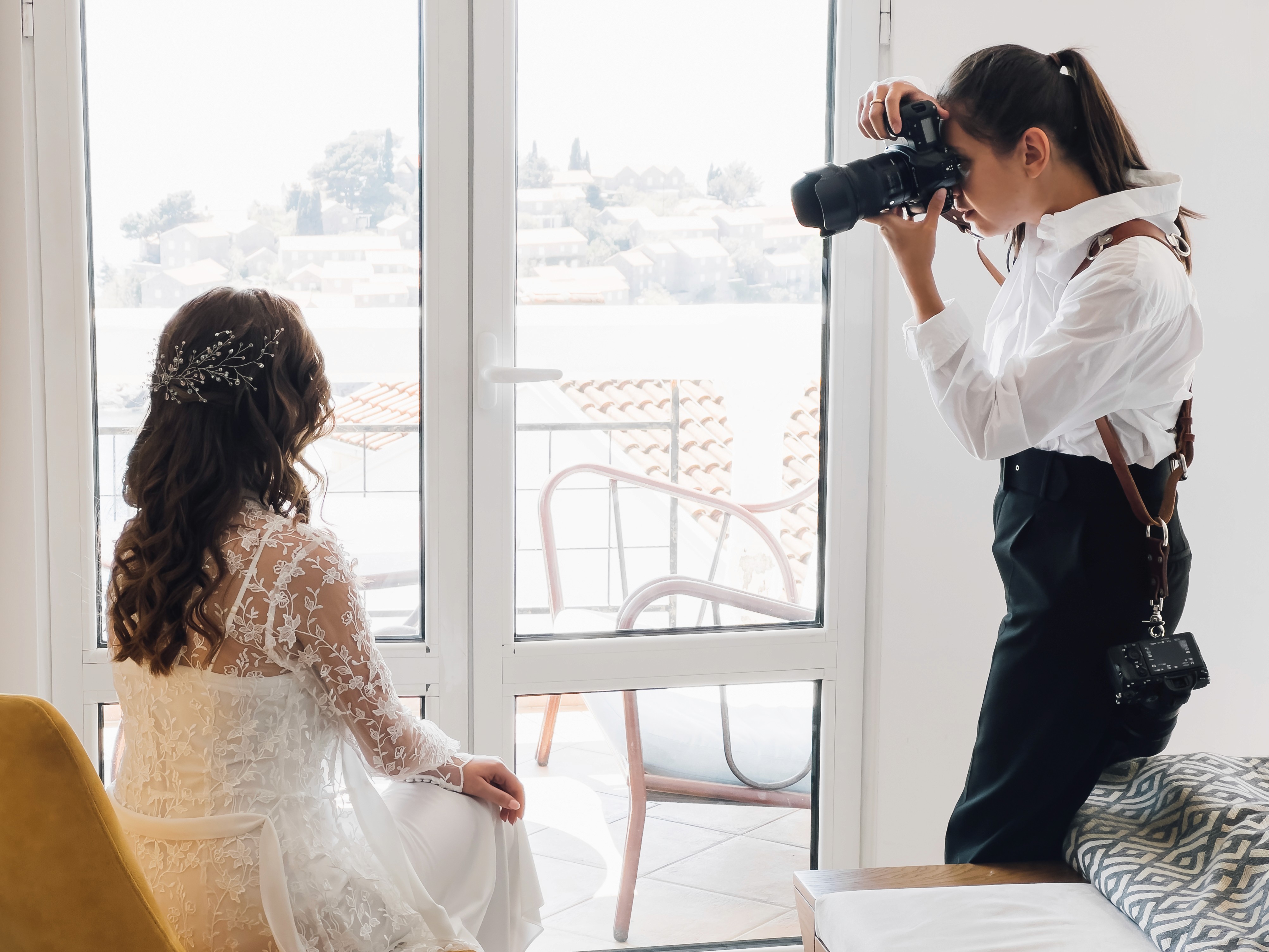 Wedding photographer capturing bride and groom at mountain overlook during golden hour