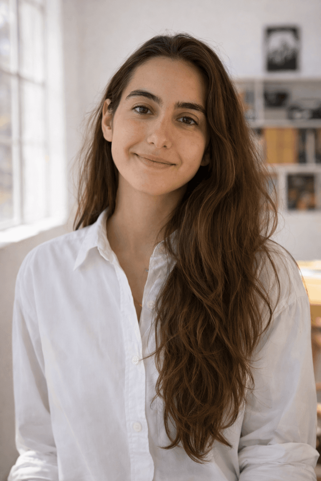 A woman with long hair dressed in a white shirt, looking directly at the camera.