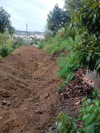 A newly cut infiltration swale in bare earth
