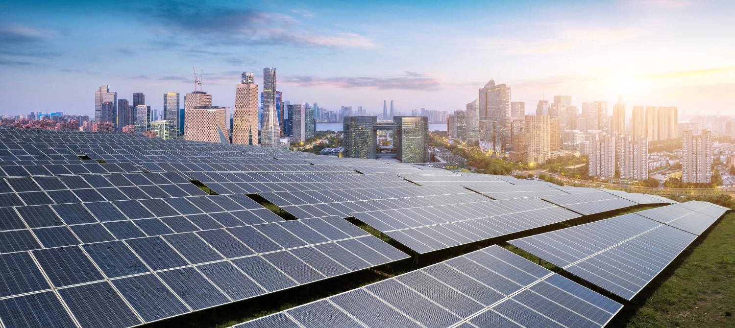 Extensive solar panel field in foreground, modern city skyline at sunset.
