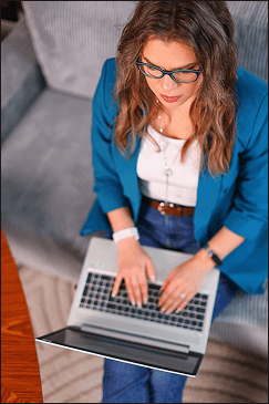 Top-down view of a designer’s workspace with a laptop, handwritten notes, coffee, and soft pink peonies, representing thoughtful website and brand strategy work