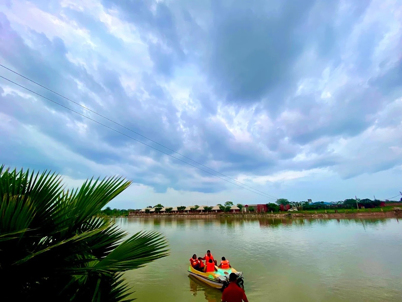 Restaurant interior with wooden tables and chairs lined against a textured wall, softly lit by round wall lamps.