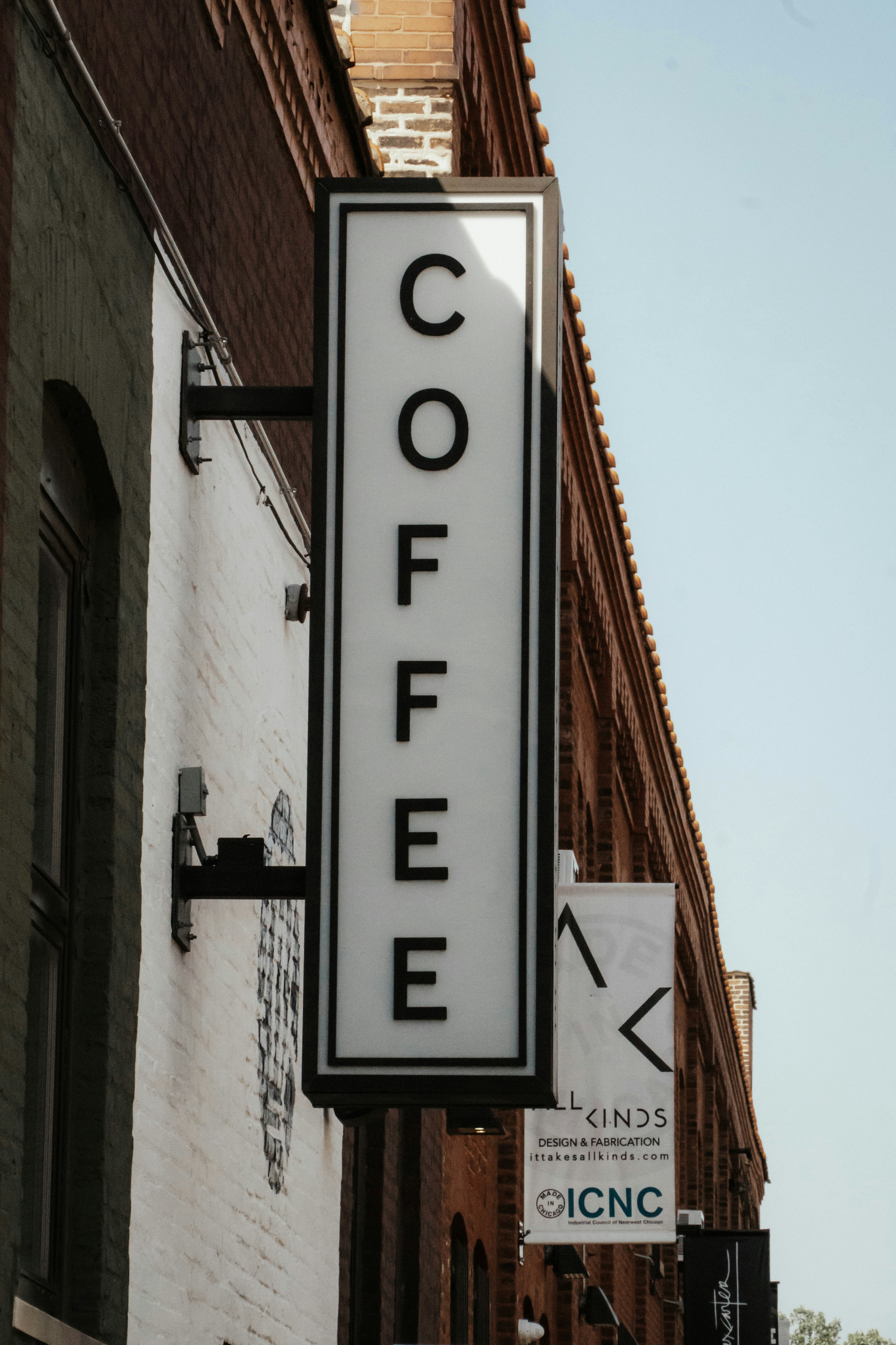 a coffee sign hanging from the side of a building